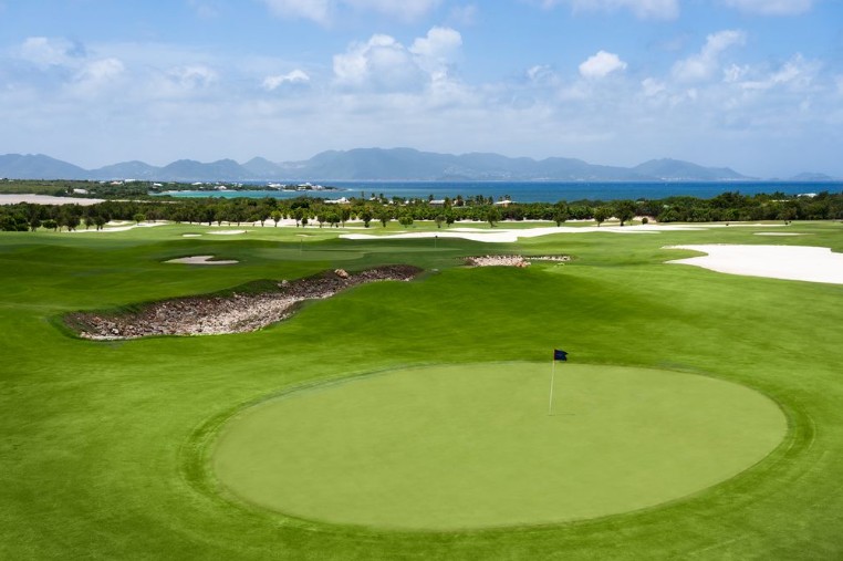 Panoramic view from Aurora Anguilla Golf Course with lush fairways overlooking the Caribbean Sea and the island of St. Maarten in the distance.